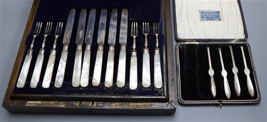 A cased set of twelve pairs of George V mother of pearl handled silver fruit eaters and four silver lobster picks.
